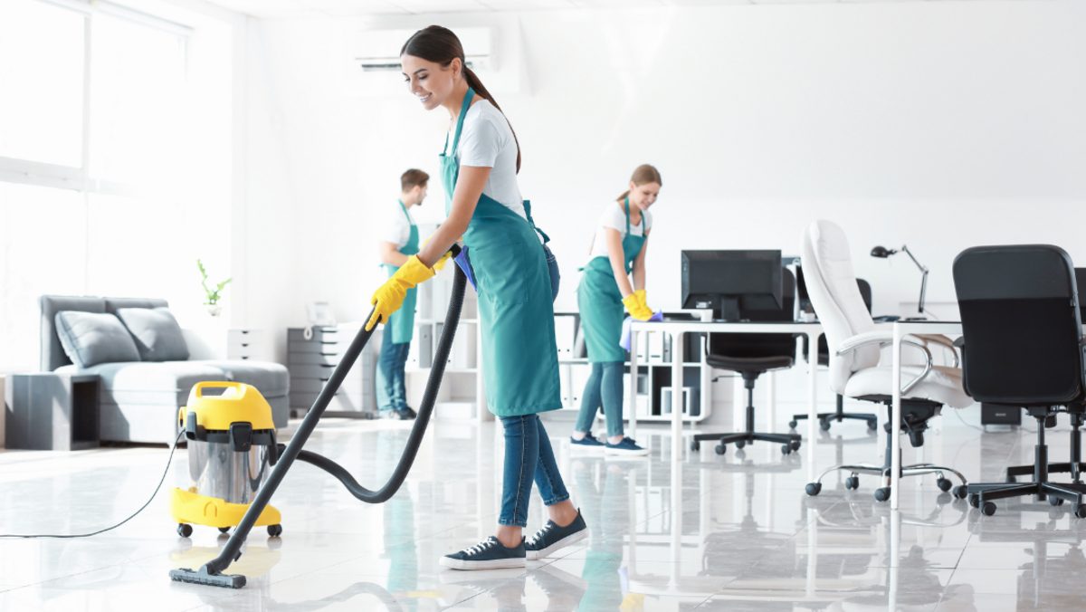 Cleaning team vacuuming and wiping desks in a bright modern office